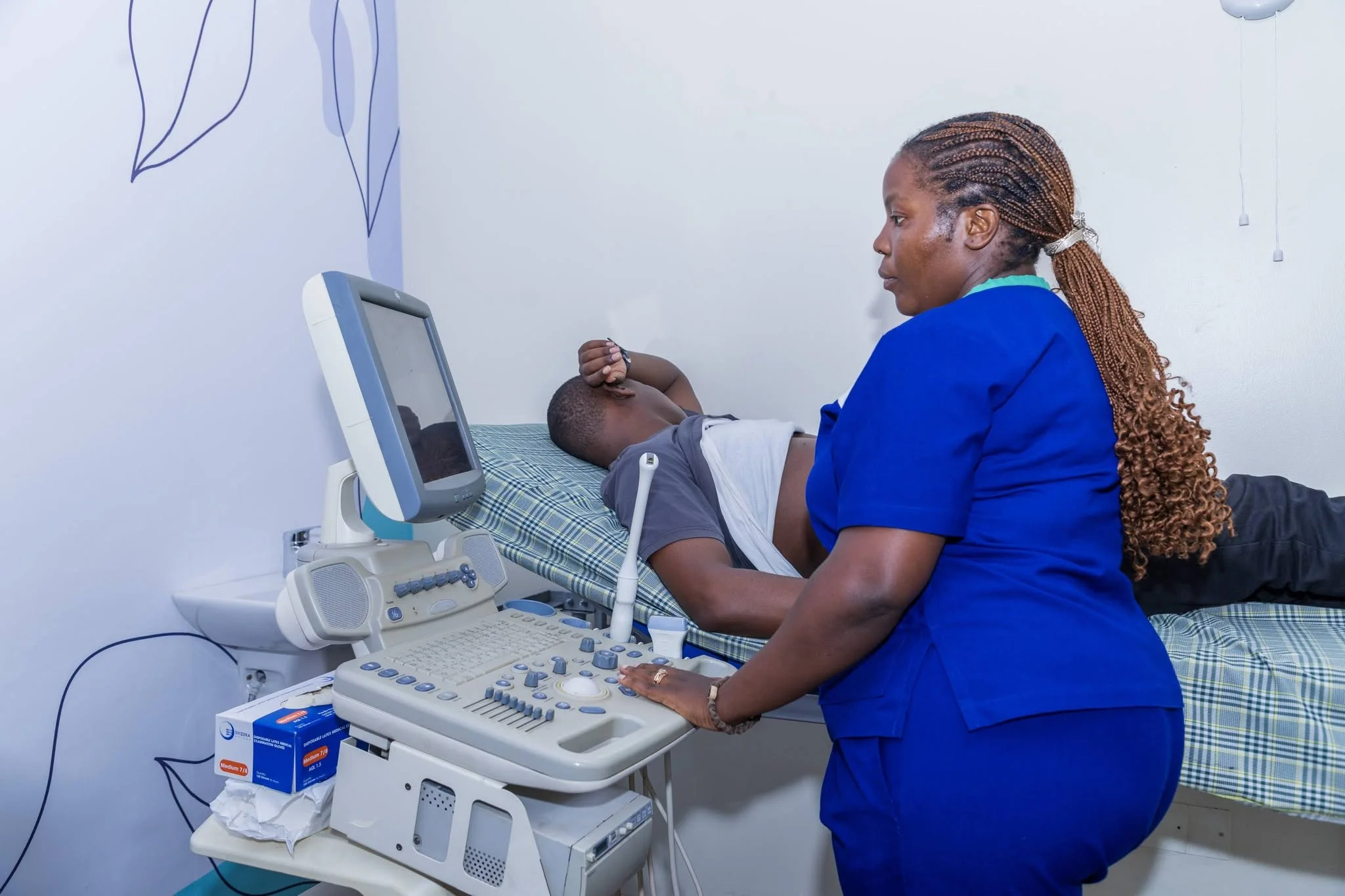 Healthcare professional operating an ultrasound machine at Case Clinic Bweyogerere