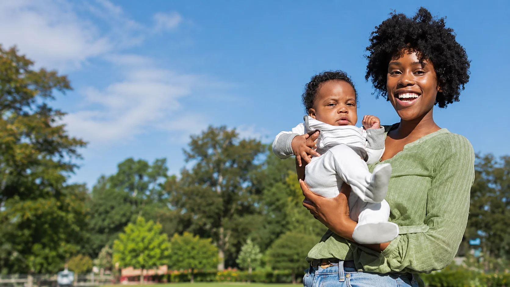 Mother holding her baby outdoors for family planning after childbirth guidance